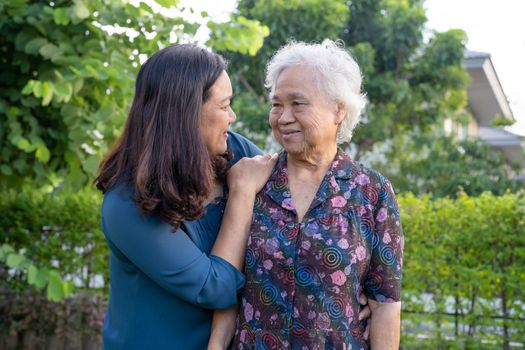 Asian elderly woman with caregiver walking with happy in nature park.