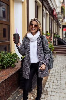 woman tourist walking around the city in sunglasses with a cup of coffee.