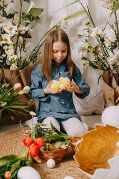 Two girls in a beautiful Easter photo zone with flowers, eggs, chickens and Easter bunnies. Happy Easter holiday