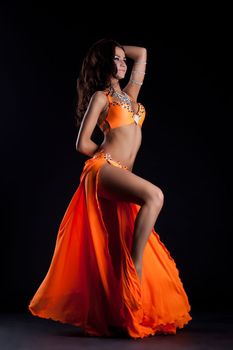 Oriental dancer in orange dress on black background