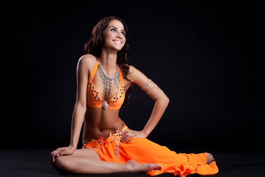 Studio portrait of happy oriental dancer in orange costume