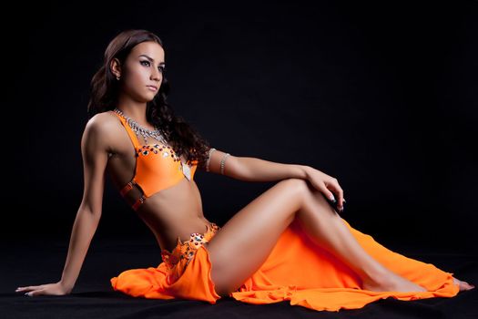 Oriental dancer sitting on floor on dark background