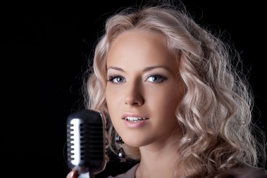 Portrait of young woman with microphone in dark