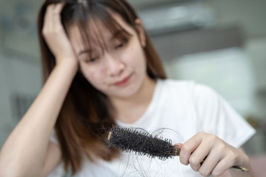 Asian woman have problem with long hair loss attach to comb brush.