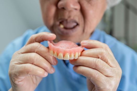 Asian senior or elderly old woman patient holding to use denture in nursing hospital ward, healthy strong medical concept