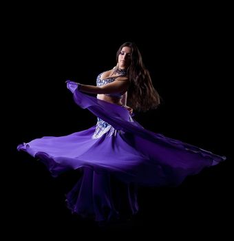 Brunette young woman dancing oriental dance Isolated on black