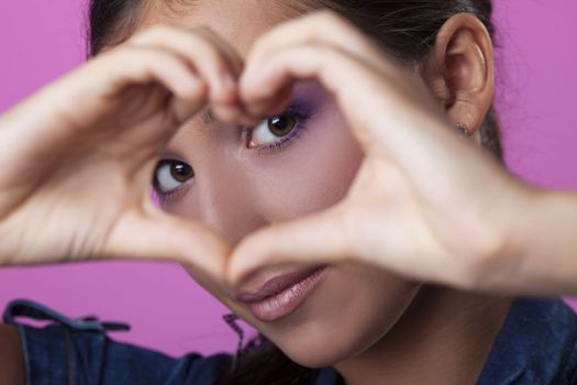 Portrait of young woman making heart with hands