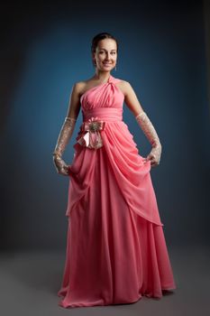 Beauty woman posing in rose fashion evening portrait on blue