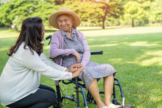 Caregiver help and care Asian senior or elderly old lady woman patient sitting on wheelchair in park, healthy strong medical concept.