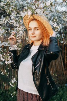 Portrait of a woman in a straw hat in a cherry blossom. Free outdoor recreation, spring blooming garden