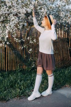 Portrait of a woman in a straw hat in a cherry blossom. Free outdoor recreation, spring blooming garden