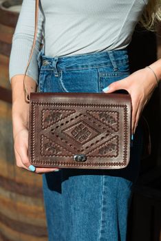 small brown women's leather bag with a carved pattern. street photo