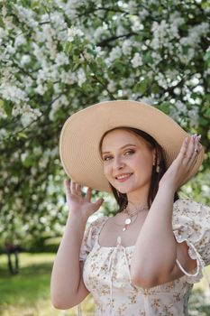 An attractive long-haired woman walks in the spring in the park of blooming apple trees. Spring portrait of a woman