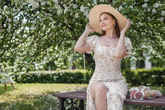 An attractive long-haired woman walks in the spring in the park of blooming apple trees. Spring portrait of a woman