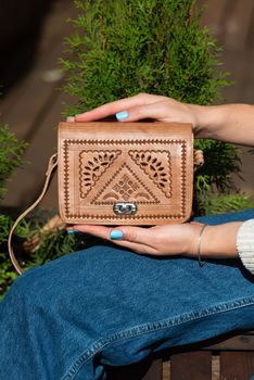 small brown women's leather bag with a carved pattern. street photo. selective focus