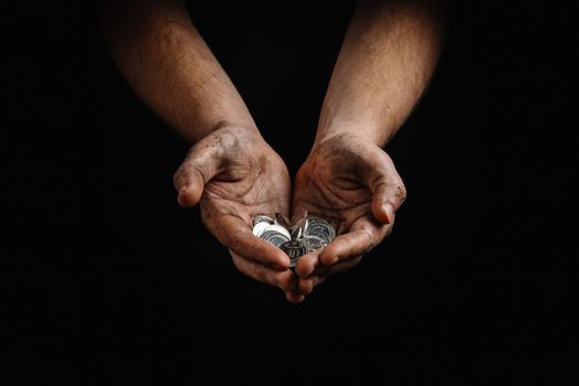 poverty in Ukraine. Dirty hands of a poor homeless man holding Ukrainian hryvnias in coins.