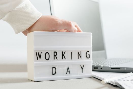 Mockup or mock-up. Workplace with a laptop, hands of a man, notepad on a white background. Freelancer's workplace. Workday text inscription and blank space for text.