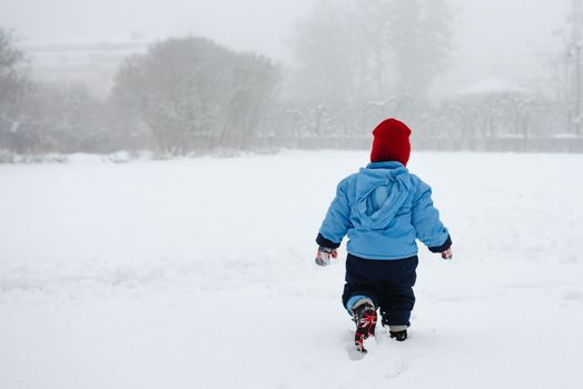 A boy walks alone in the snow.