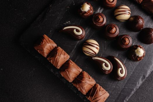 Chocolate candy on a dark background. Top view. Lots of different chocolates. An assortment of delicious chocolates.