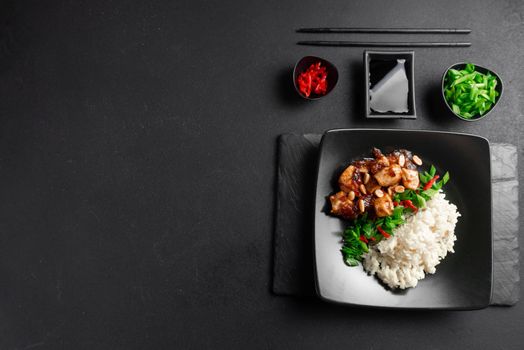 Asian Cuisine. Rice with chicken on a dark background top view. Boiled rice with stir-fried sliced chicken breast and basil.Thai cuisine.