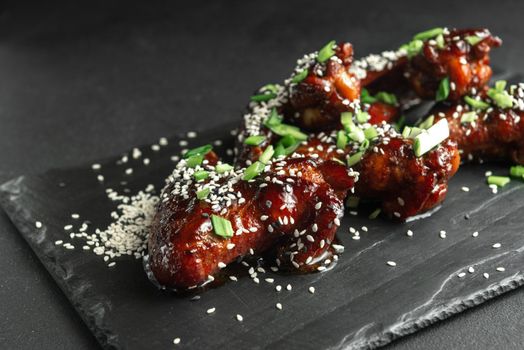 American Cuisine. Fried chicken wings with tomato sauce and sesame seeds. Traditional chicken wings in caramel sauce.