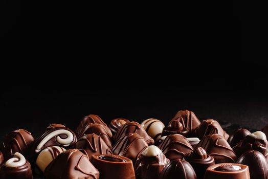 Chocolate candy on a dark background. Top view. Lots of different chocolates. An assortment of delicious chocolates