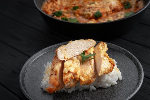 chicken breast with rice sliced into slices on a dark background in a gray plate. Chicken breast in cream sauce