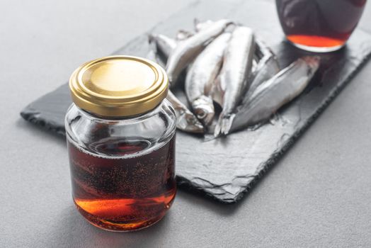 Garum is a fermented fish sauce. Prepared by fermentation from fish, salted garum sauce in a bottle on a gray background. Garum fish sauce made from anchovies on the grey background.