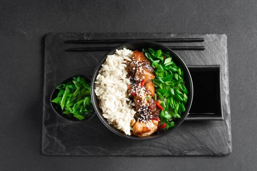 teriyaki chicken rice bowl - asian food style. Asian food. Thai food. Rice with chicken and green onions on a dark background. Chinese food. Rice with spicy kung pao chicken on a plate. horizontal view from above