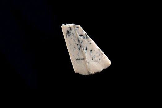 Blue cheese, dor bleu or Roquefort mold cheese on black isolate, lifestyle food.
