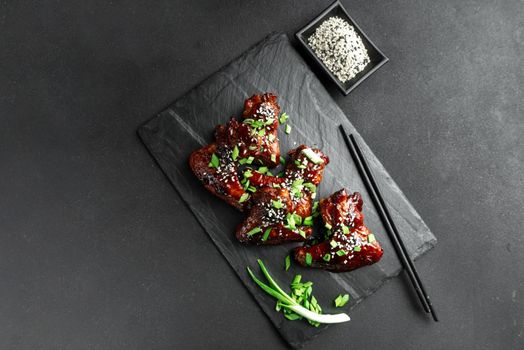 Chicken wings with sesame and green onions. Traditional Asian recipe. Dark background. Top view