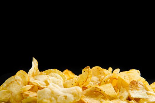 Lots of fried chips on a black background. Isolate. A place to write text. Copy space for text.