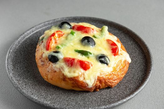 Homemade pizza with cheese, olives, tomatoes and green peppers. Top view on gray background. Mini pizza