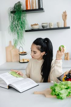 A young woman is on a diet. The woman is a vegetarian. Reads a magazine about healthy eating and lifestyle.