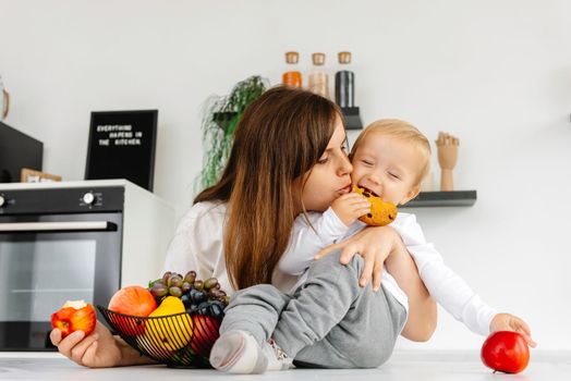 Happy Family Mom hugging baby and eating apples and healthy food. Reducetarian Eating Enjoying Vegetable Food.