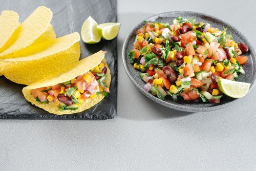 Salsa with corn and beans on a wooden backdrop with tacos. Mexican Cuisine. Empty space for the text. Copy space