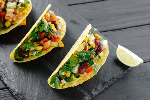Tacos with salsa. Mexican tacos with vegetarian filling on a dark background. Trend 2022 Reducetarian, flexitarian, pescatarian eating. Top view