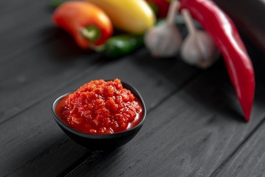 Hot chili pepper paste. Red sauce on a wooden background. Ajika or ajika in Georgian cuisine or harissa in Arab cuisine. View from above