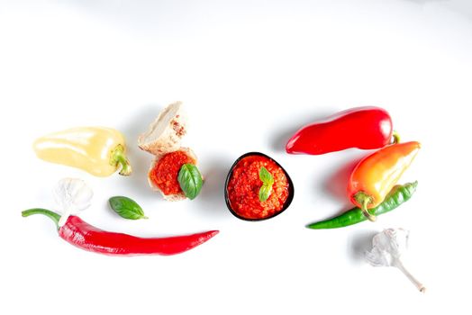 Turkish-style biber salcasi pepper paste. Black bowl with red sauce and fresh peppers isolated on a white background.