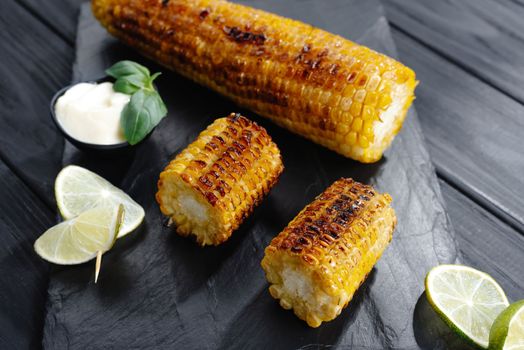 Grilled corn on slate to serve with sauce and lime. Top view