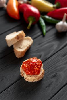 Toast with ajika, on a wooden dark background. The ingredients are side by side