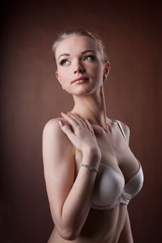 Beautiful woman portrait in white bra on brown background