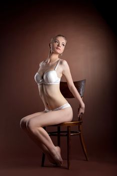 sexy woman portrait in white bra sit on old style chair