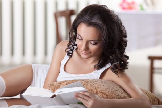 Cute woman read book in morning interior look at camera