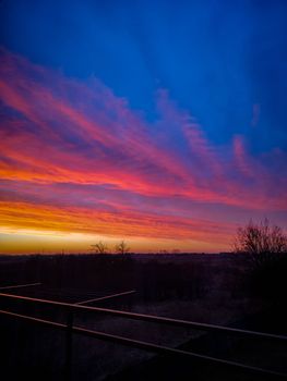 Beautiful colorful morning sunrise full of clouds seen from balcony with long metal railings