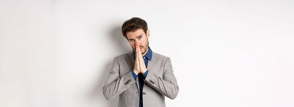 Please help. Pleading man in suit asking for favour, begging you, standing on white background.