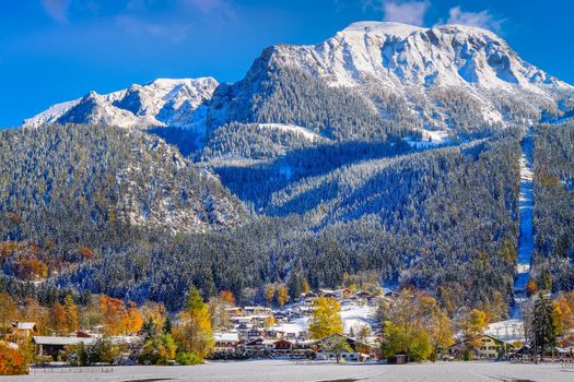 Road into snowy mountain and pine woods in bavarian Alps at autumn, Germany