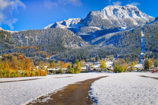 Road into snowy mountain and pine woods in bavarian Alps at autumn, Germany