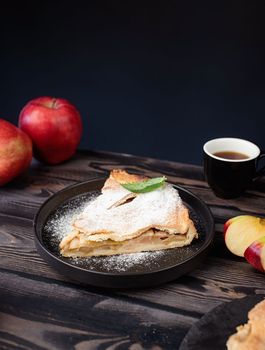 Autumn food. Homemade piece of apple pie with fresh red apples on black table