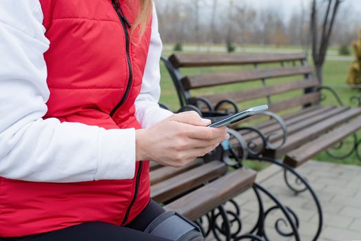 Woman wearing sport clothes and knee brace or orthosis after leg surgery, walking down the stairs in the park. Medical and healthcare concept.